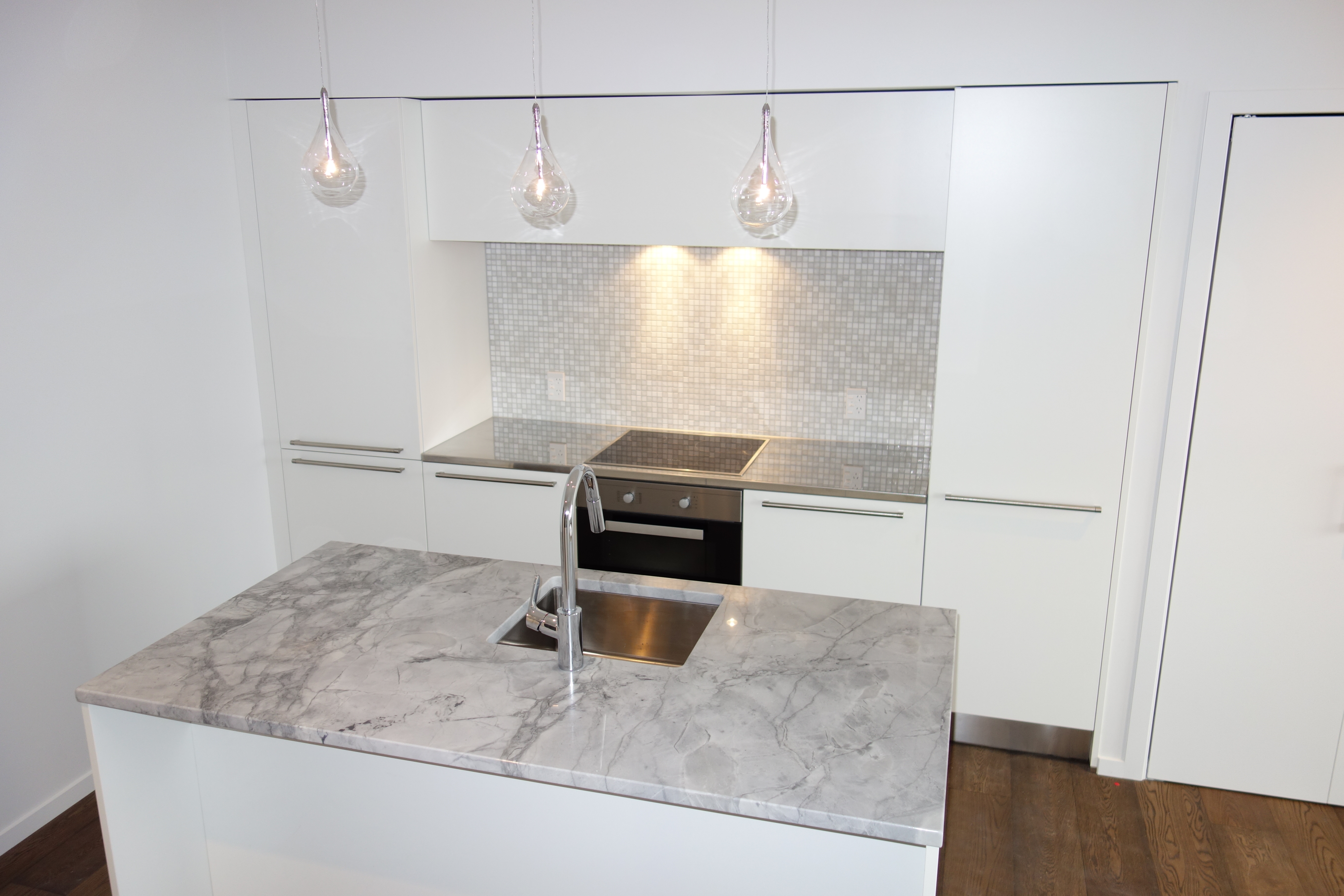 Matt white kitchen with grey granite island and mosaic splashback